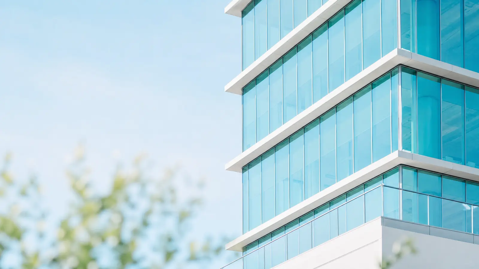 A glass and steel office building with reflections of clouds